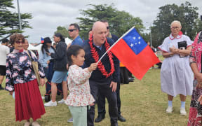 A girl shows her Samoan flag to Prime Minister Christopher Luxon, at the Auckland Pasifika Festival, Western Springs, on 9 March 2024.