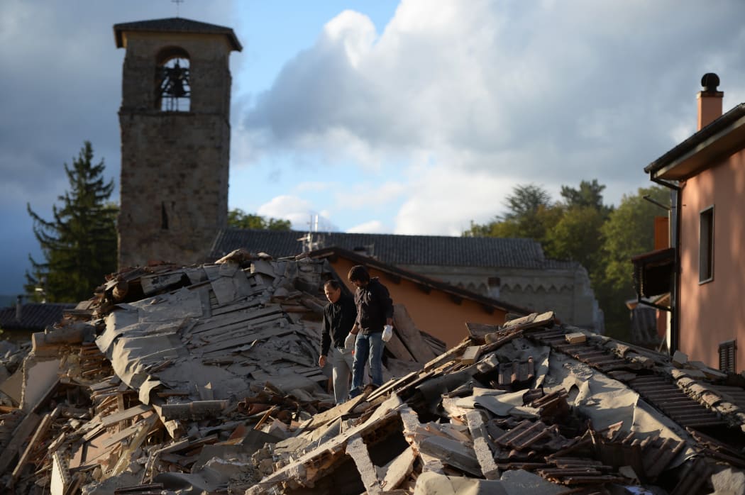 Two men walk on a damaged home after a strong heartquake hit Amatrice