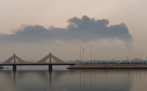 A plume of smoke rises after a reported Iranian strike on fuel tanks in Muharraq on March 12, 2026. Oil soared above $100 and stocks sank on March 12 as Iran's fresh attempts to hit supplies in the Middle East and threats to bring down the global economy overshadowed a record release of strategic crude by the International Energy Agency. Bahrain reported Iran had carried out an attack on fuel tanks in the country, while Saudi Arabia said it had intercepted drones headed to Shaybah oil field and drones struck fuel tanks at Oman's Salalah port, where operations were subsequently suspended.