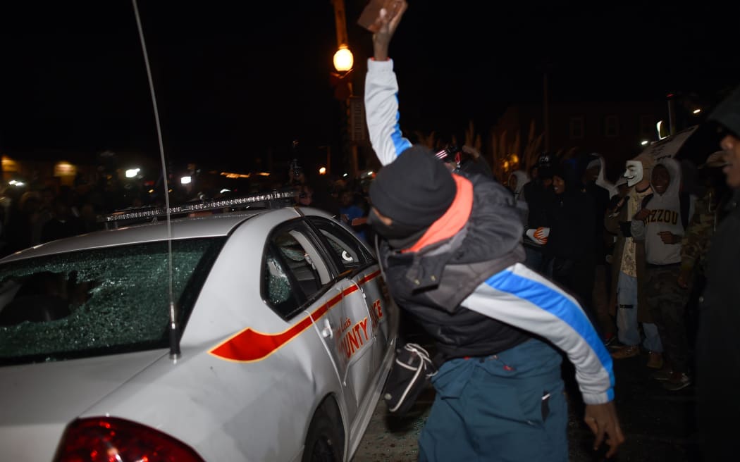 A demonstrator attacks a police car after hearing the police officer who shot Michael Brown will not face charges.