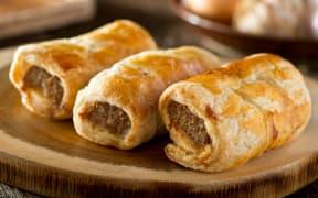 Delicious homemade sausage rolls on a wooden serving platter.