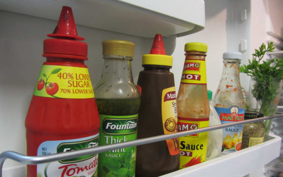 An array of sauces in a fridge drawer