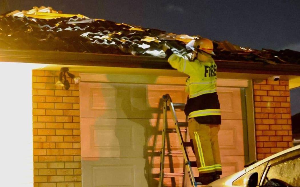 A FENZ worker attends to a damaged roof at Erne Crescent in East Tāmaki, Auckland on 9 April.