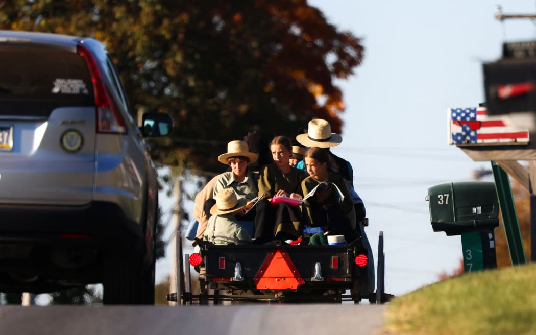 An Amish family rides in a horse-drawn buggy on a road shared with cars in Strasburg, Pennsylvania, 19 October, 2024.