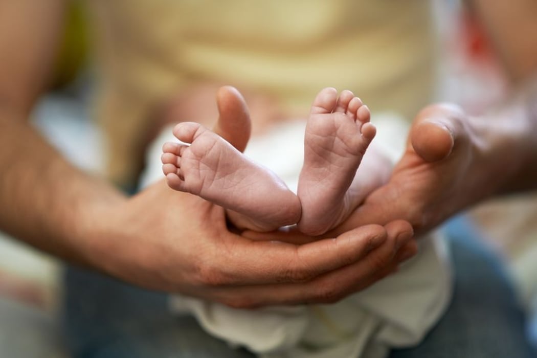 A father holds his child's feet (file)