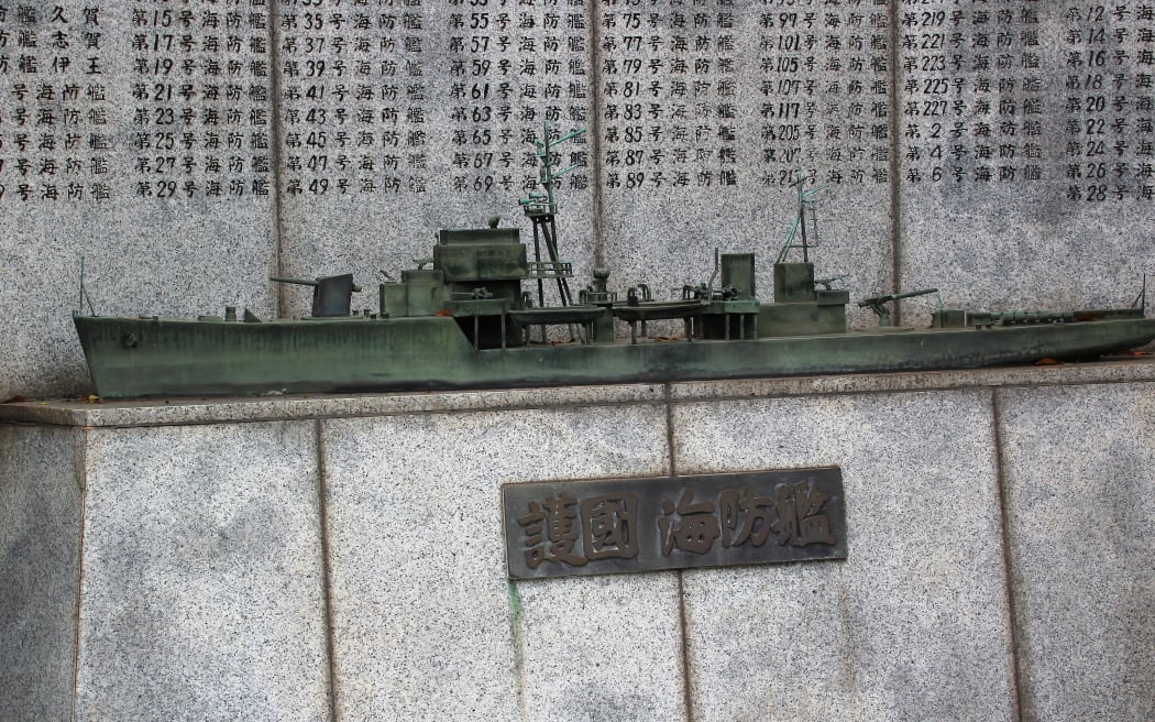 Bronze warship sculpture in front of names of the dead in Japanese