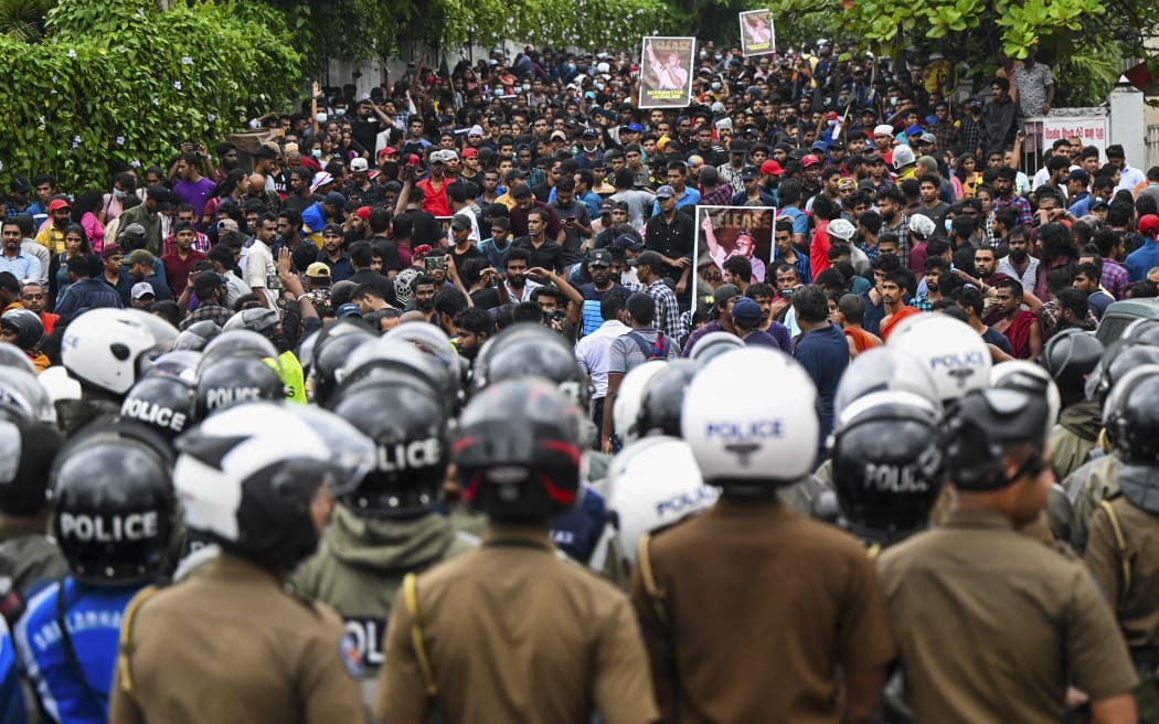 Policemen stand guard as protestors take part in an anti-government demonstration by the university students demanding the release of their leaders, in Colombo on October 18, 2022.