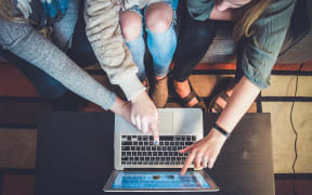 three girls looking at a laptop
