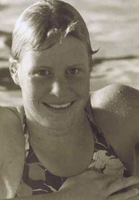 A portrait of Olympic and Commonwealth Games swimmer Rebecca Perrott leaning on the edge of a swimming pool and smiling at the camera.