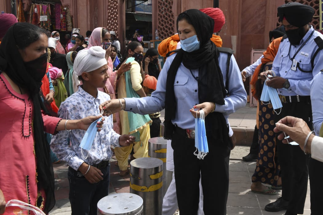 Private security guards distribute facemasks to people during an awareness campaign against the spread of the Covid-19 coronavirus, in Amritsar on 4 April 2021.