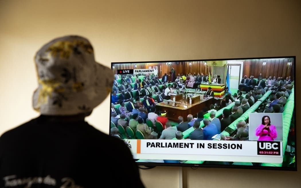 A Ugandan transgender woman who was recently attacked and currently being sheltered watches a TV screen showing the live broadcast of the session from the Parliament for the anti-gay bill, at a local charity supporting the LGBTQ Community near Kampala on March 21, 2023. - Uganda's parliament was due to vote on March 21, 2023 on anti-gay legislation which proposes tough new penalties for same-sex relations in a country where homosexuality is already illegal.
Under the proposed law, anyone in the conservative East African nation who engages in same-sex activity or who identifies publicly as LGBTQ could face up to 10 years in prison. (Photo by STUART TIBAWESWA / AFP)