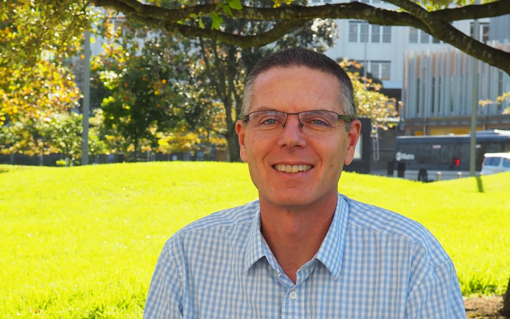 Professor Warwick Bagg, acting dean Faculty of Medical and Health Sciences at the University of Auckland wears a blue check button up shirt with glasses smiling.