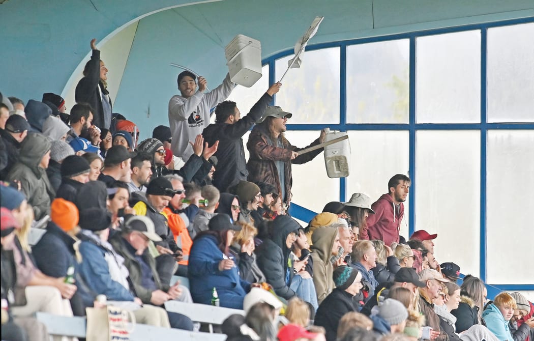 Thistle fans in the stand at Childers Road Reserve take to their feet to cheer on their players.
