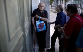 Pensioners wait outside a branch of the National Bank of Greece to receive their benefits, limited to €120, in Athens on 17 July 2015.