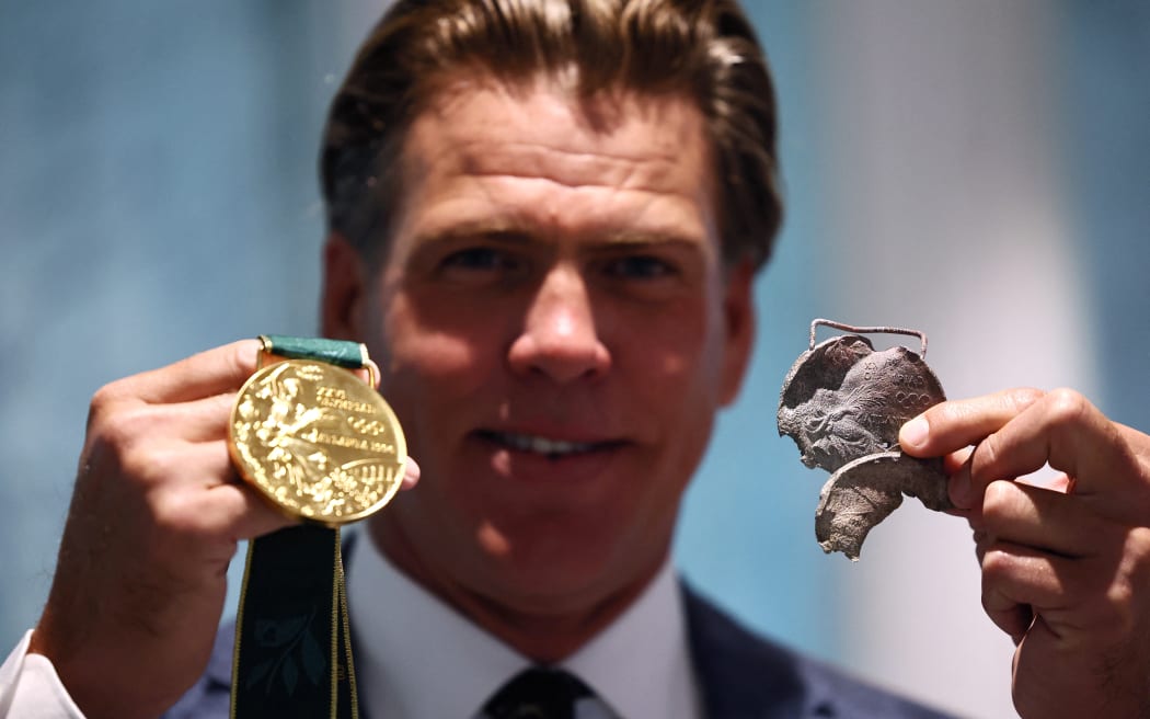 US swimmer Gary Hall Jr.  holds one of the original medals as he is presented with repilicas of his Olympic medals by  IOC President Thomas Bach during a handover ceremony after the originals were destroyed with his house in the Los Angeles wildfires in 2025.