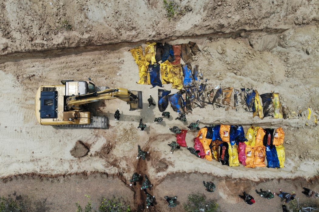 Indonesian soldiers burying quake victims in a mass grave in Poboya in Indonesia's Central Sulawesi after an earthquake and tsunami hit the area on September 28.