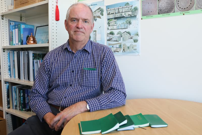 University of Auckland professor Paul Kilmartin sitting at his office, with green Collins diaries on the table and one in his shirt pocket.