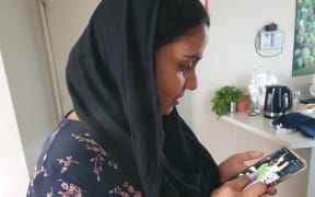 An photo of Gagandeep Kaur looking at an image of her daughter, Nimrat who is still in India.