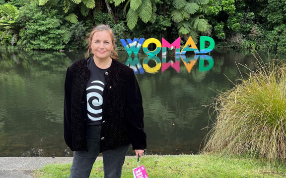 Charlotte Ryan standing in front of the Womad sign