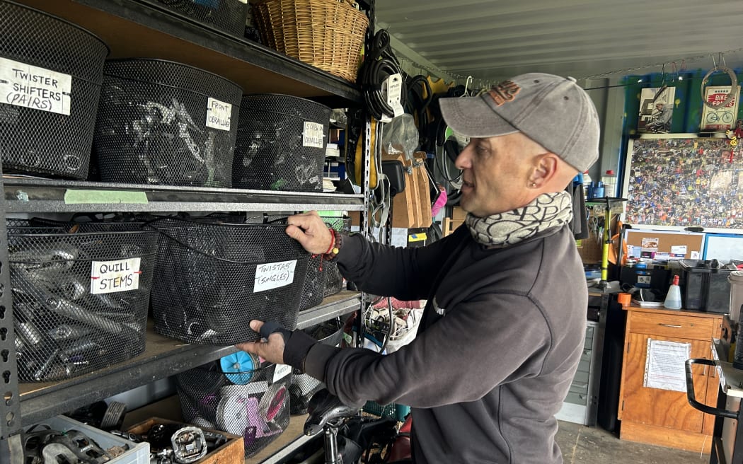 Picture of a man getting bike parts from a shelf.