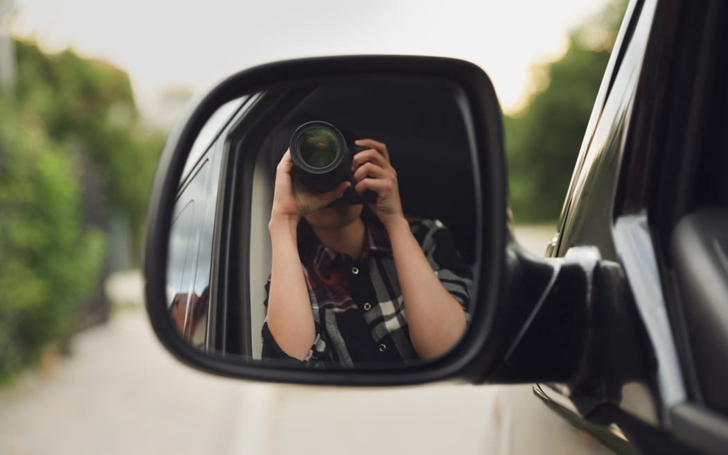 Private detective with camera spying from a car.