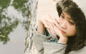 A sad Asian girl resting her head on her hands