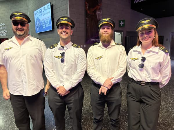 Three men and one woman dressed as pilots.