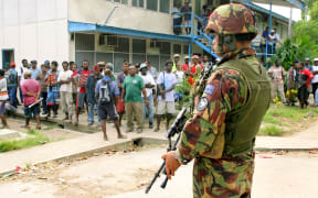 Locals look on as New Zealand soldiers and police guard the Honiara Magistrates Court in 2006, when opposition member of parliament Charles Dausabea appeared in court.