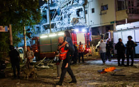 EDITORS NOTE: Graphic content / An Israeli first responder evacuates an injured resident from a site hit by a missile fired from Iran, in Ramat Gan on the outskirts of Tel Aviv on June 13, 2025. Iran fired a barrage of ballistic missiles at Israel in a counter-strike on June 13, after an unprecedented onslaught hammered the Islamic republic's top military brass and targeted its nuclear facilities and bases. (Photo by GIL COHEN-MAGEN / AFP)