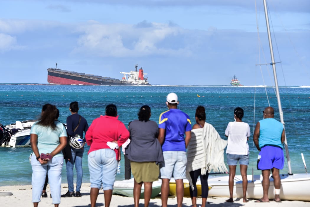 Bystanders look at MV Wakashio bulk carrier that had run aground and from which oil is leaking near Blue Bay Marine Park in south-east Mauritius on August 6, 2020. - The carrier, belonging to a Japanese company but Panamanian-flagged, ran aground on July 25 and its crew was evacuated safely.