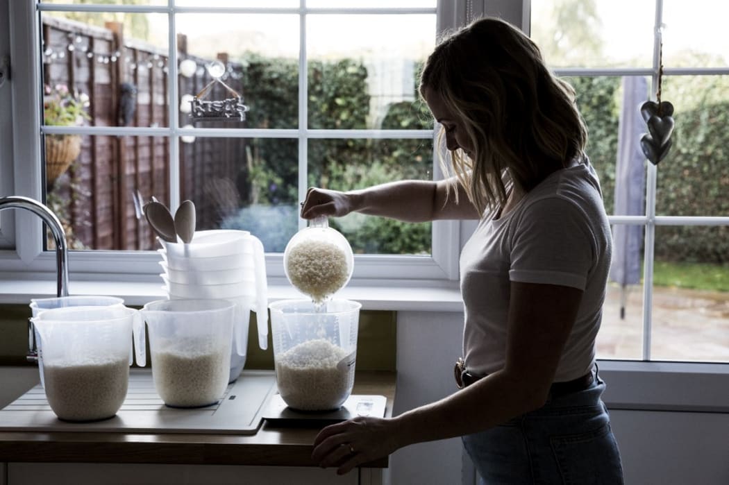 [England] Woman standing in a domestic kitchen, making jar candles. (Photo by Mint Images / Mint Images / Mint Images via AFP)