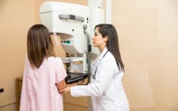 Doctor setting a patient in the correct position to get a mammogram. Breast cancer screening.
