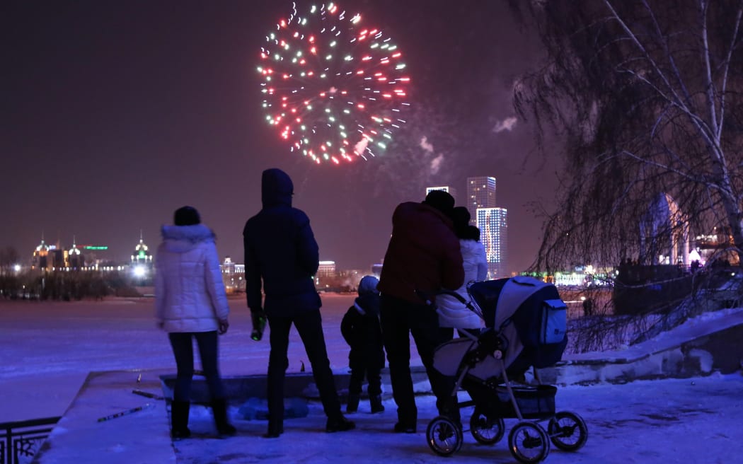 People watch fireworks displayed for the New Year celebrations over Ishim River in Kazakhstan capital city Astana.