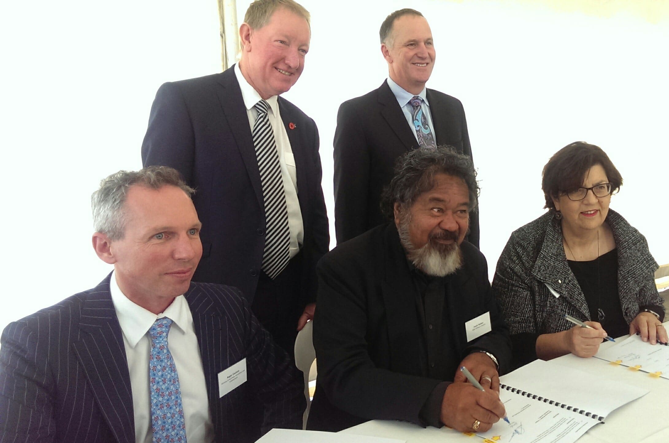 Haahi Walker of Ngāti Whātua o Kaipara, centre, signs the Memorandum of Understanding.