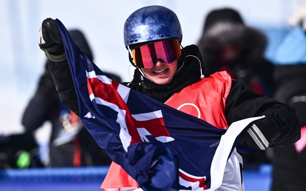 Nico Porteous holds the NZ flag after winning the freestyle skiing men's freeski halfpipe final run during the Beijing 2022 Winter Olympic Games