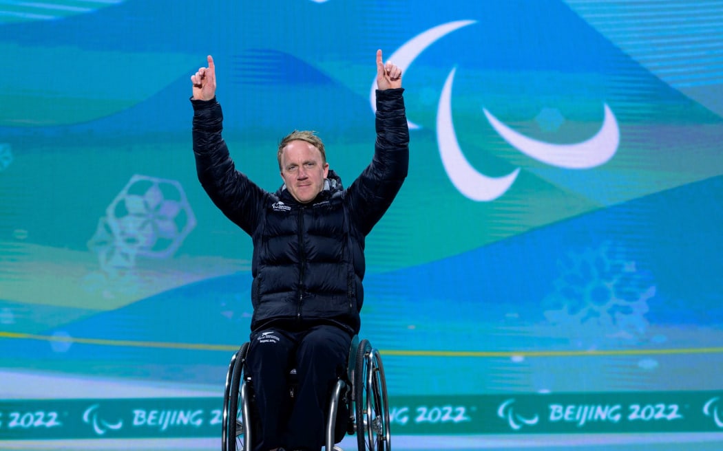 Corey Peters NZL celebrates on the podium after winning gold in the Men’s Downhill Sitting Para Alpine Skiing, 2022 Winter Paralympic Games.