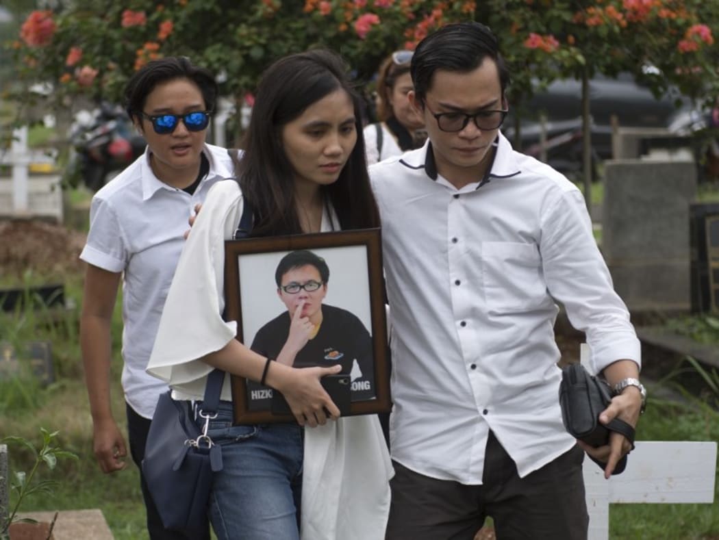 The sister of Hizkia Jorry Saroinsong, a passenger on the Lion Air flight, carries her brother's portrait during his funeral in Jakarta.