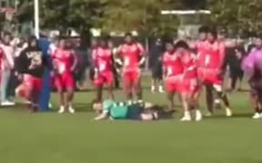 A referee is pushed over at a club rugby match in Auckland, September 2024.