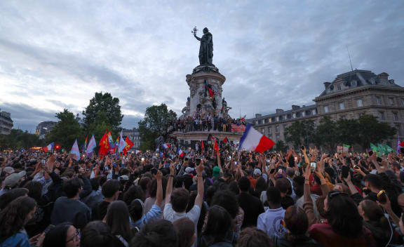 Participants wave French national tricolours during an election night rally following the first results of the second round of France's legislative election at Place de la Republique in Paris on July 7, 2024. A loose alliance of French left-wing parties thrown together for snap elections was on course to become the biggest parliamentary bloc and beat the far right, according to shock projected results.