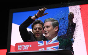 A protester throws glitter on Britain's main opposition Labour Party leader Keir Starmer (R) at the start of his keynote address to delegates on the third day of the annual Labour Party conference in Liverpool, northwest England, on October 10, 2023. (Photo by Oli SCARFF / AFP)