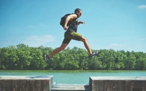 Man leaping over a gap in a walkway