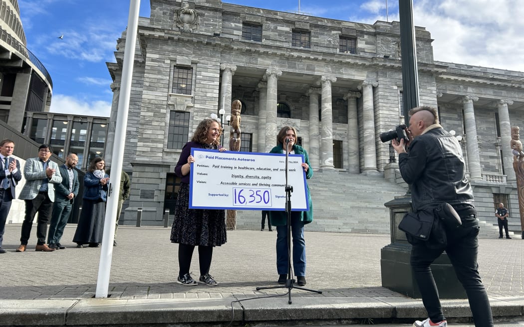 Organiser Bex Howells hands Paid Placements Aotearoa's petition to Labour MP Jan Tinetti.