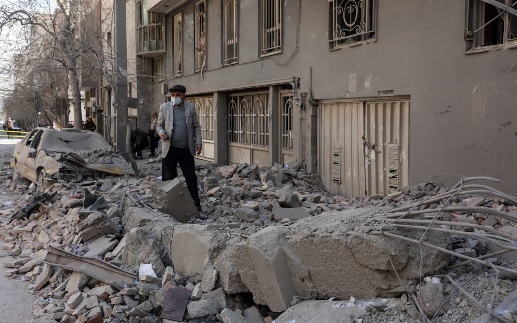 A man makes his way through debris littering a street following airstrikes in central Tehran, on March 4, 2026. Iran's Revolutionary Guards said on March 4, they had total control of the Strait of Hormuz, a key waterway for global energy transit, as Israel launched a new wave of strikes on the Iranian capital. (Photo by AFP)