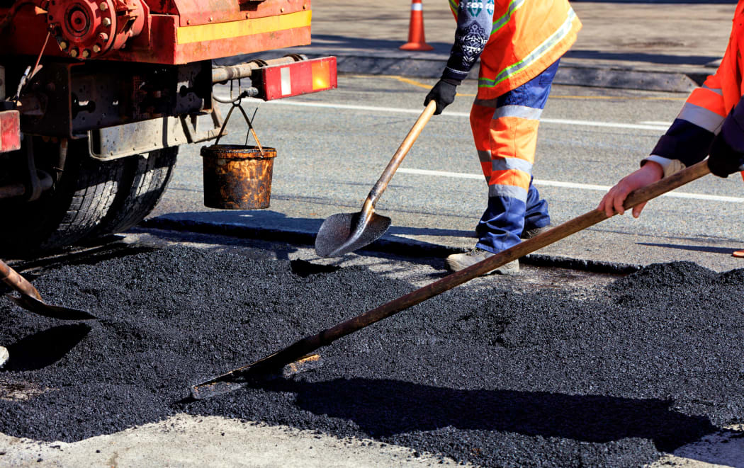 The road workers' working group renews a part of the road with fresh asphalt and levels it for repair in road construction.