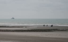 This photograph taken on January 14, 2024, on the beach of Wimereux, northern France, shows French military ship patrolling in the English Channel. Five migrants died on the night of 13 to 14 January 2024 near the beach of Wimereux (Pas-de-Calais) as they tried to reach a boat overboard in freezing water to cross the English Channel, the first fatal tragedy of 2024 off the French coast. (Photo by Bernard BARRON / AFP)