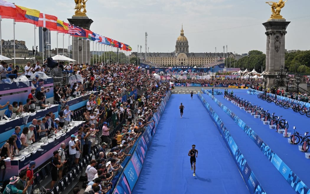 Britain's Alex Yee runs toward the finish line ahead of New Zealand's Hayden Wilde and France's Leo Bergere to win the running stage during the men's individual triathlon at the Paris 2024 Olympic Games in central Paris on July 31, 2024. (Photo by Andrej ISAKOVIC / AFP)