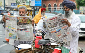 Men read local newspapers with frontpage articles on India-Pakistan conflict in Amritsar on May 8, 2025 a day after India launched strikes on Pakistan. The nuclear-armed rivals exchanged small arms and artillery fire overnight along the de facto border in contested Kashmir, the Indian army said May 8. (Photo by Narinder NANU / AFP)