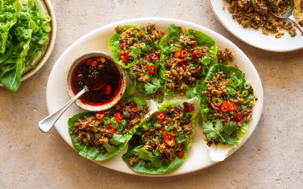 A platter showing lettuce leaf cups filled with spicy cumin lamb fried rice, garnished with sliced chilli.