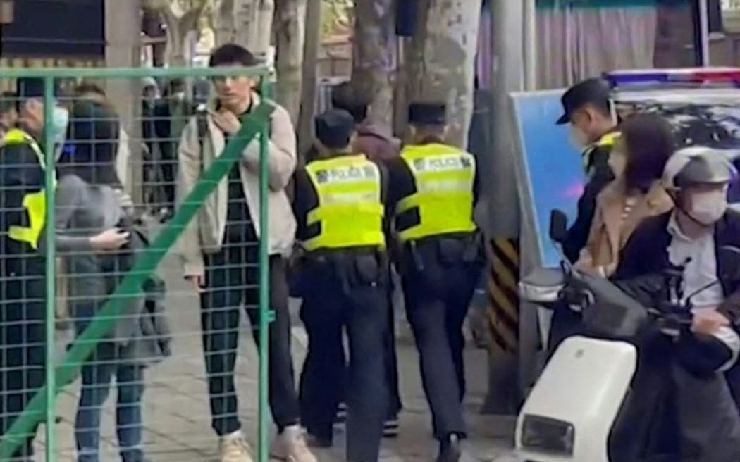 This frame grab from AFPTV video footage shows police detaining a person on Wulumuqi street, named for Urumqi in Mandarin, in Shanghai on November 28, 2022, where protesters gathered over the weekend to protest against China's Covid-19 restrictions following a deadly fire in Urumqi, the capital of the Xinjiang region.