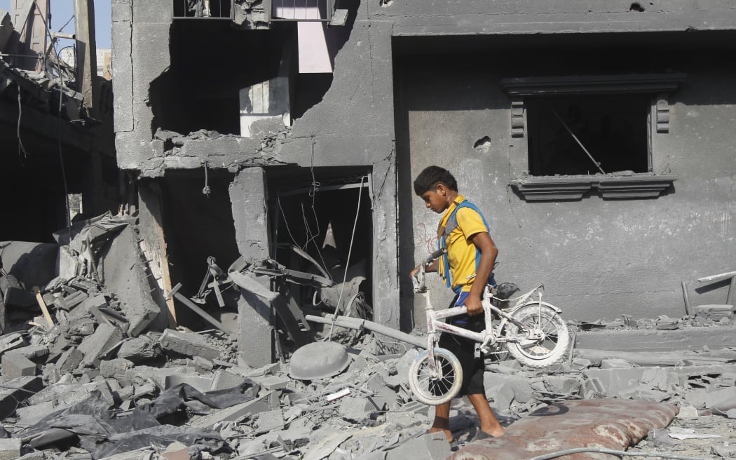 A Palestinian youth carries a bicycle from the wreckage of a building hit in an Israeli strike, in Rafah,